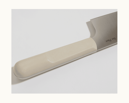 Close-up of the Everyday Chef’s Knife featuring a cream-colored handle and a partially visible full-tang blade made from durable German steel, displayed on a light background.