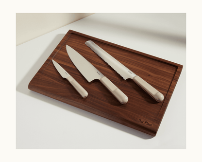A wooden cutting board with three beige-handled kitchen knives, including the Everyday Chef’s Knife with a full-tang German steel blade, plus a paring knife and a serrated bread knife.