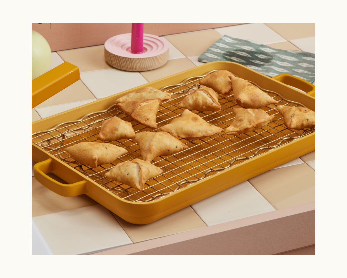 The Golden Fry Set includes a yellow tray with a cooling rack, ideal for serving golden-brown, triangular pastries—perfect treats to enjoy during Diwali celebrations.