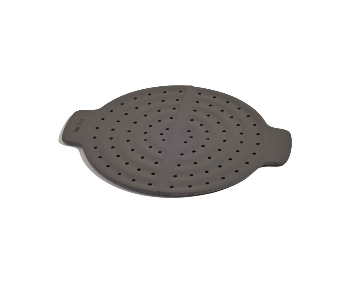 The Fearless Fry is a round, dark gray silicone steamer basket with handles and evenly spaced holes, designed for steaming food in your Always Pan while helping to prevent splatter.