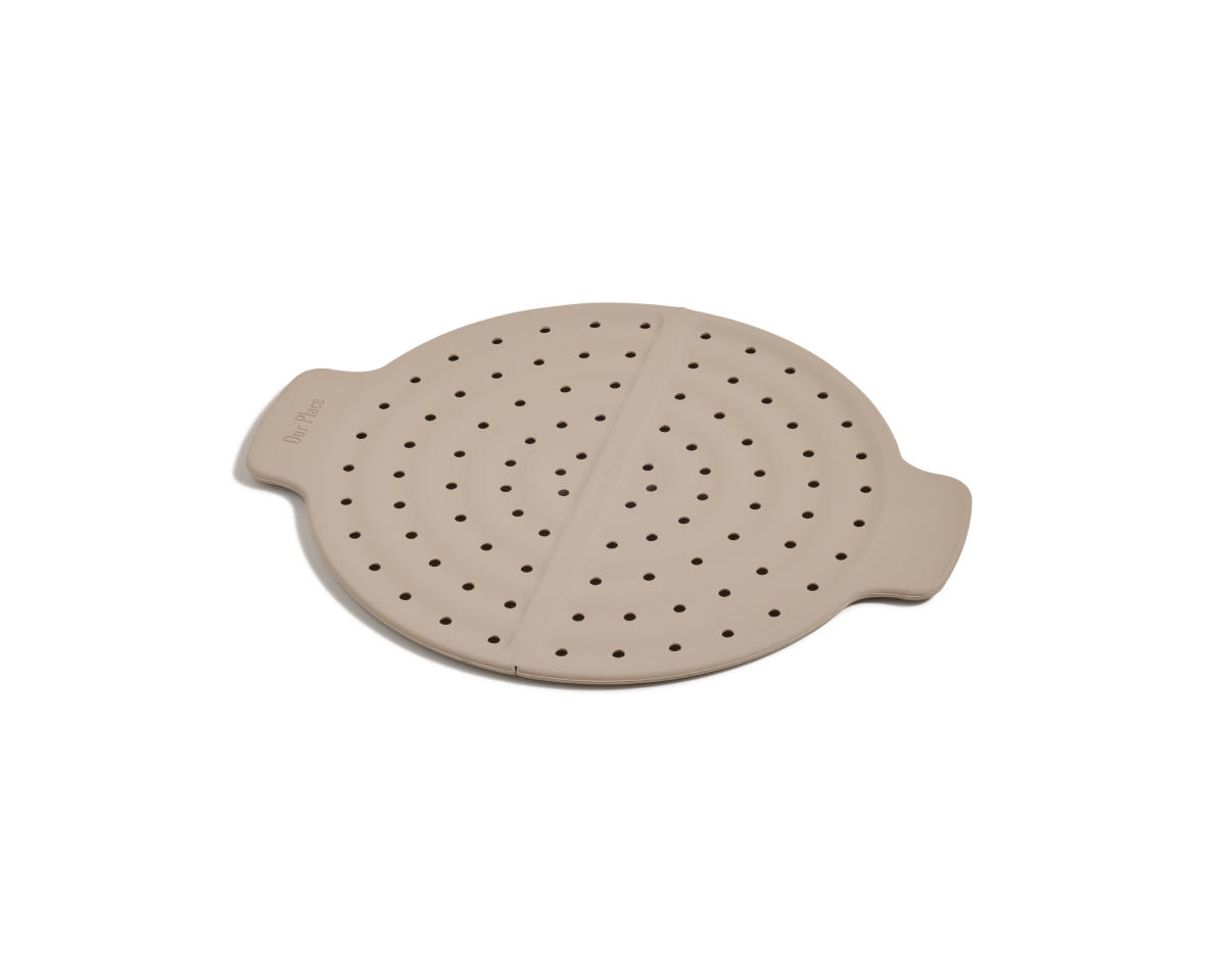 The Fearless Fry is a round, beige silicone steamer insert with side handles and multiple small holes, designed to prevent splatter in your Always Pan. Shown here on a plain white background.