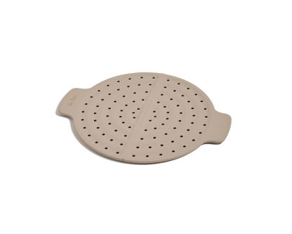 The Fearless Fry is a round, beige silicone steamer insert with side handles and multiple small holes, designed to prevent splatter in your Always Pan. Shown here on a plain white background.