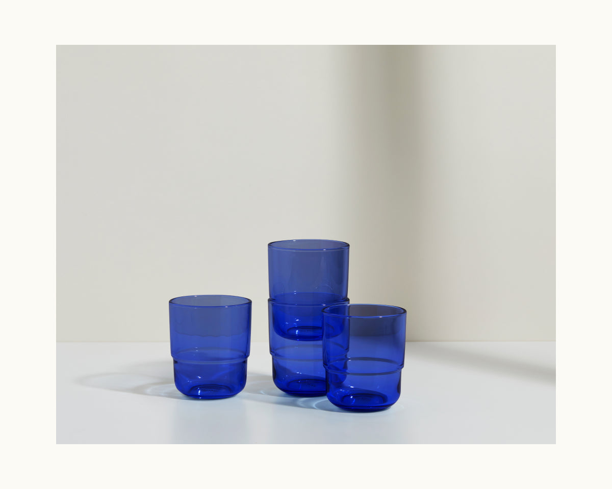 Three Short Night + Day Glasses made from translucent blue recycled glass, each a different height, are arranged on a white surface with a light background.