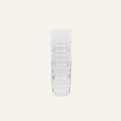 Four Short Night + Day Glasses, handmade from recycled glass, are stacked vertically against a plain, light background.