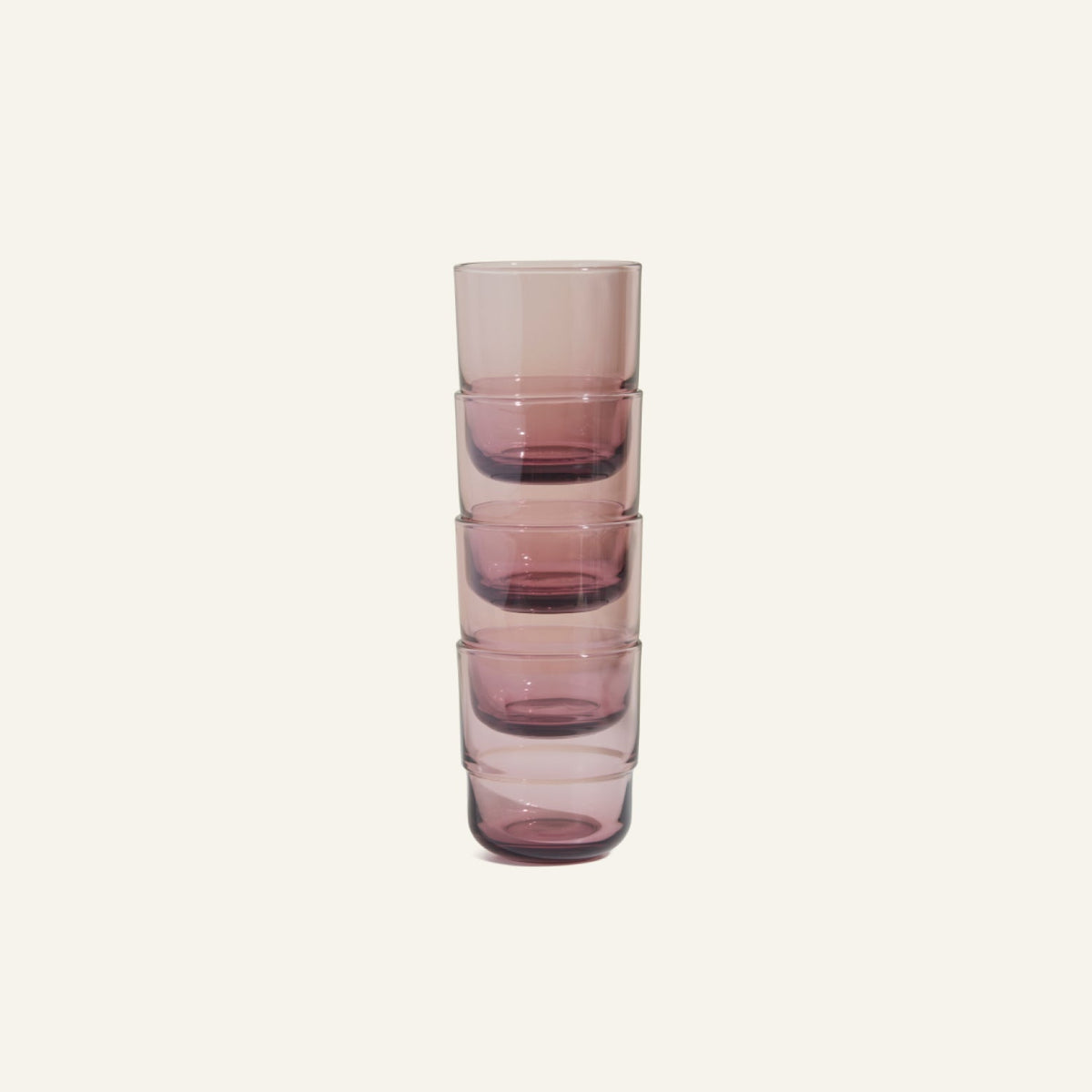 A stack of five Short Night + Day Glasses, made from transparent, purple-tinted recycled glass, sits on a plain light background.