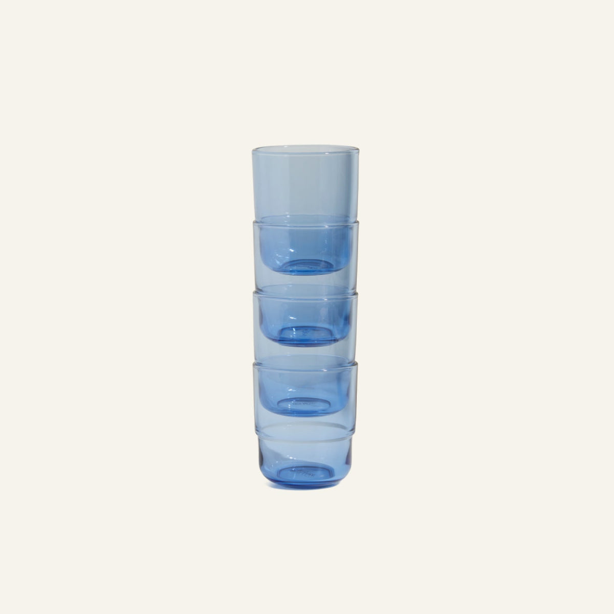A set of five Short Night + Day Glasses, crafted by hand in transparent blue, is stacked vertically against a plain light background.