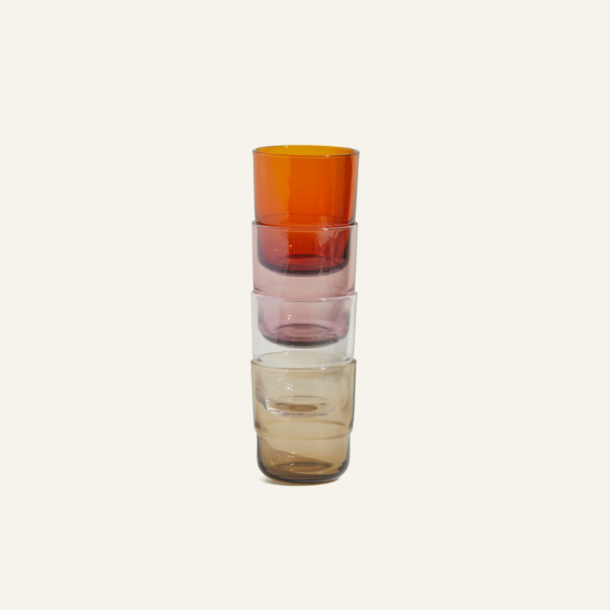 A set of four handmade Short Night + Day Glasses in orange, pink, light brown, and beige. Each colorful tumbler is displayed against a plain background for a modern look.