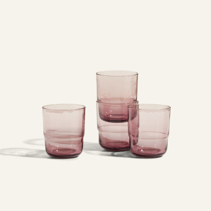 Four Short Night + Day Glasses, each with a purple tint and handmade design, are arranged in a staggered stack on a light background.