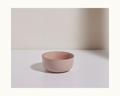 A pink ceramic Soup Bowl from a chic bowl set rests on a white surface with a neutral background.