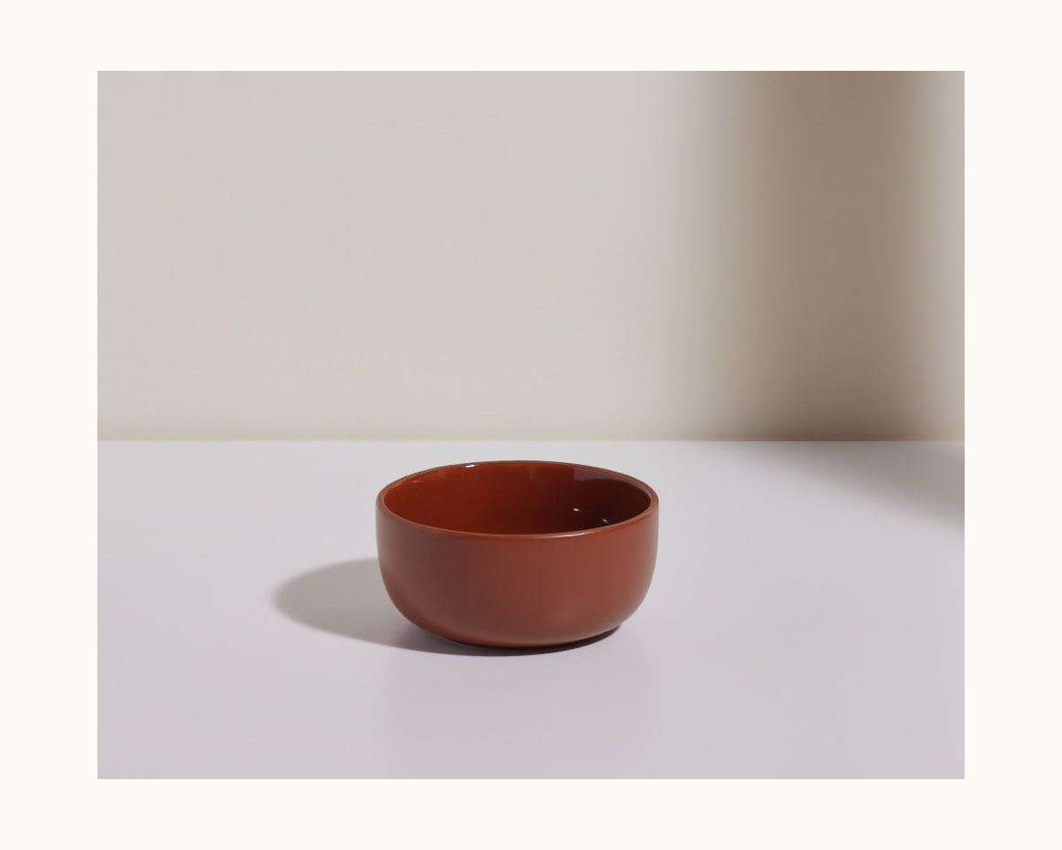 A small, round, brown ceramic Soup Bowl from a stackable collection sits on a white surface against a neutral background.