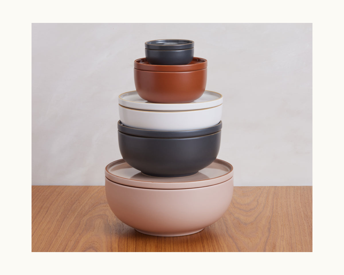 Tiny Bowls are four stackable, scratch-resistant ceramic bowls in assorted colors and sizes, neatly stacked on a wooden surface against a neutral background—perfect for everyday use.