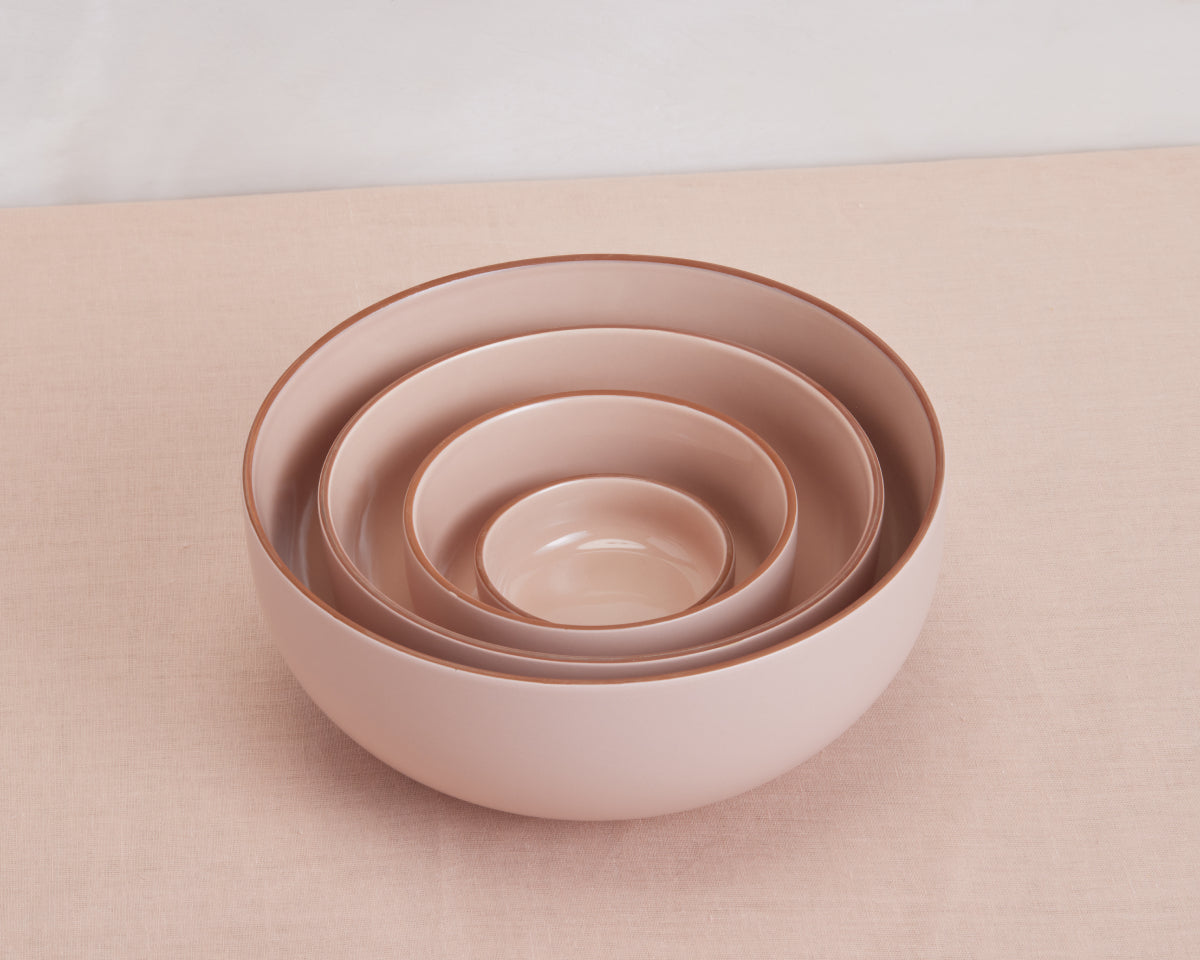 Four light pink Tiny Bowls of different sizes are stacked together on a matching surface, highlighting elegant, scratch-resistant, and stackable ceramic tableware.