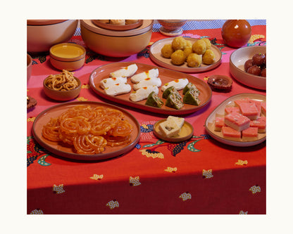 Indian sweets and snacks served in Tiny Bowls, arranged on a red patterned tablecloth.
