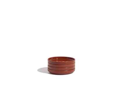 A small stack of three round, brown Tiny Plates ceramic snack plates is placed on a plain white background.