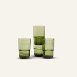 Three Tall Night + Day Glasses in green, featuring a minimalist stackable design, are arranged in a staggered formation on a plain light background.
