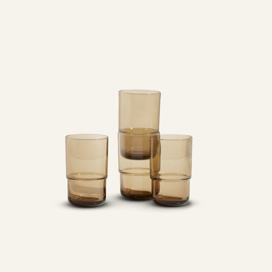 Four Tall Night + Day Glasses in amber are arranged with two stacked and two standing individually against a plain, light background.