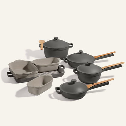 The Cookware + Bakeware Set in neutral gray includes an Always Pan, three lidded pots with wooden handles, three rectangular baking dishes, and a metal roasting pan—a versatile choice for any kitchen.