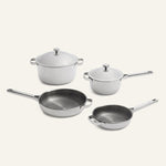 Titanium Pro Cookware Set 2.0 featuring two lidded stainless steel pots and two frying pans with silver handles and light gray exterior surfaces.