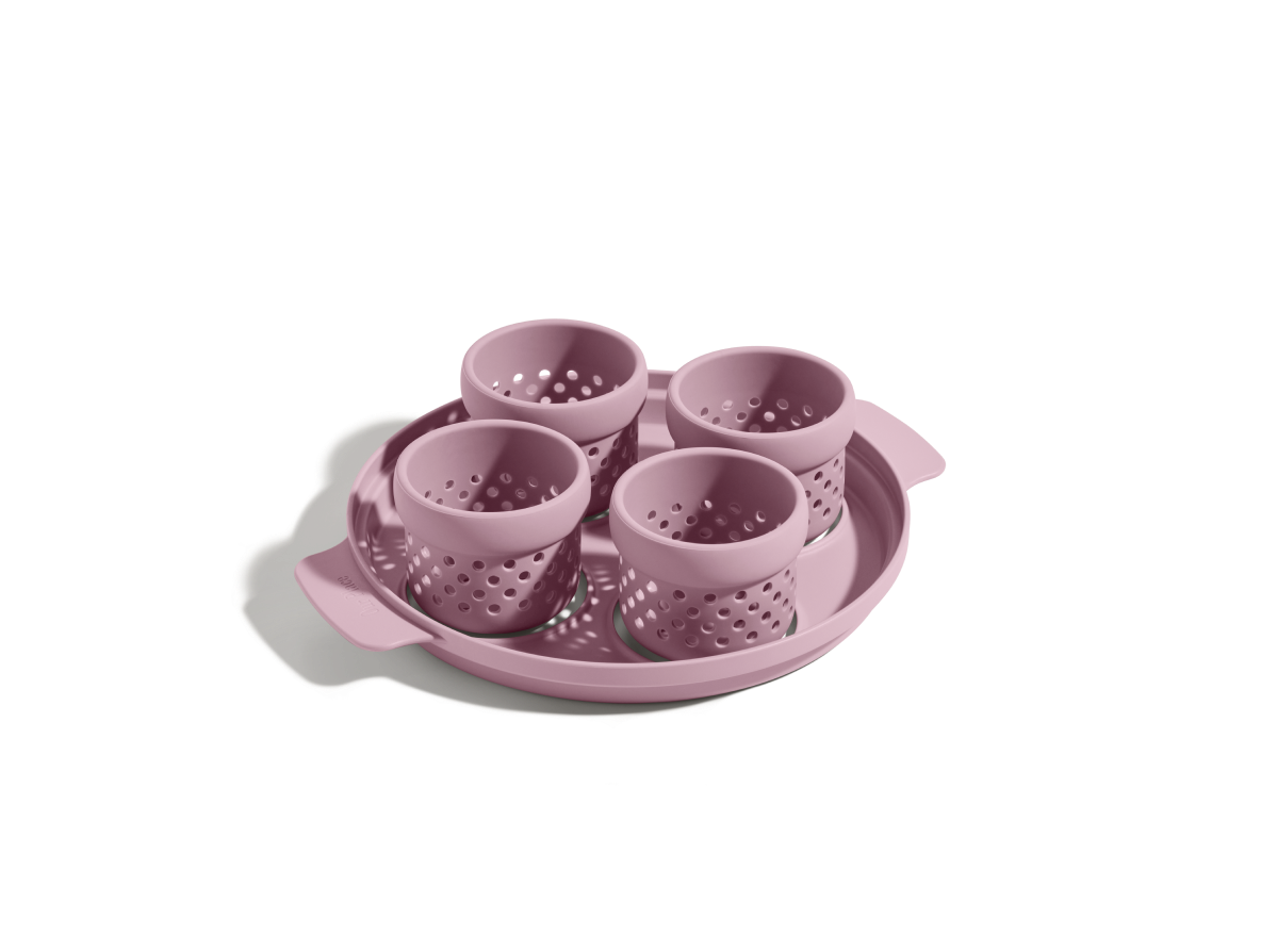 The Egg Poacher includes four pink silicone cups on a matching round tray with handles, ideal for making poached eggs, displayed on a white background.