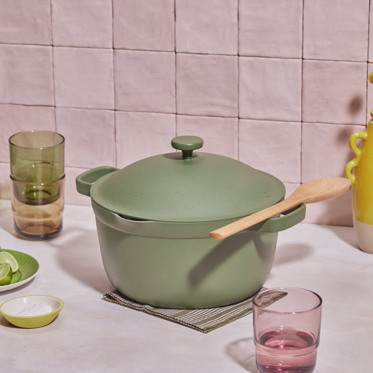 Green perfect pot non toxic nonstick dutch oven resting on a table next to drinking glasses