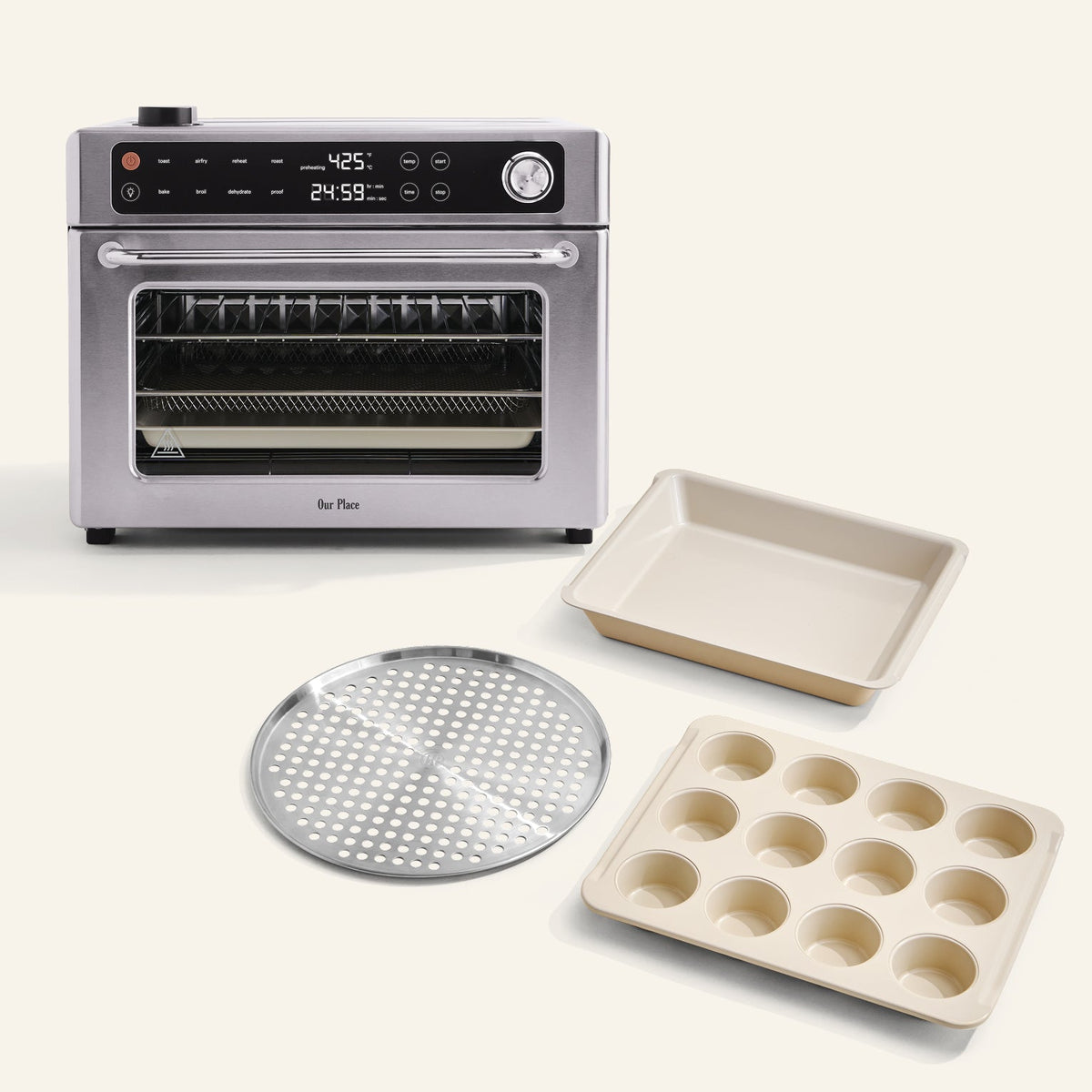 The Wonder Oven Pro + Wonder Oven Pro Chef's Kit, a stainless steel countertop oven with digital controls, is shown with a muffin tin, square baking pan, and round perforated tray on a light background.