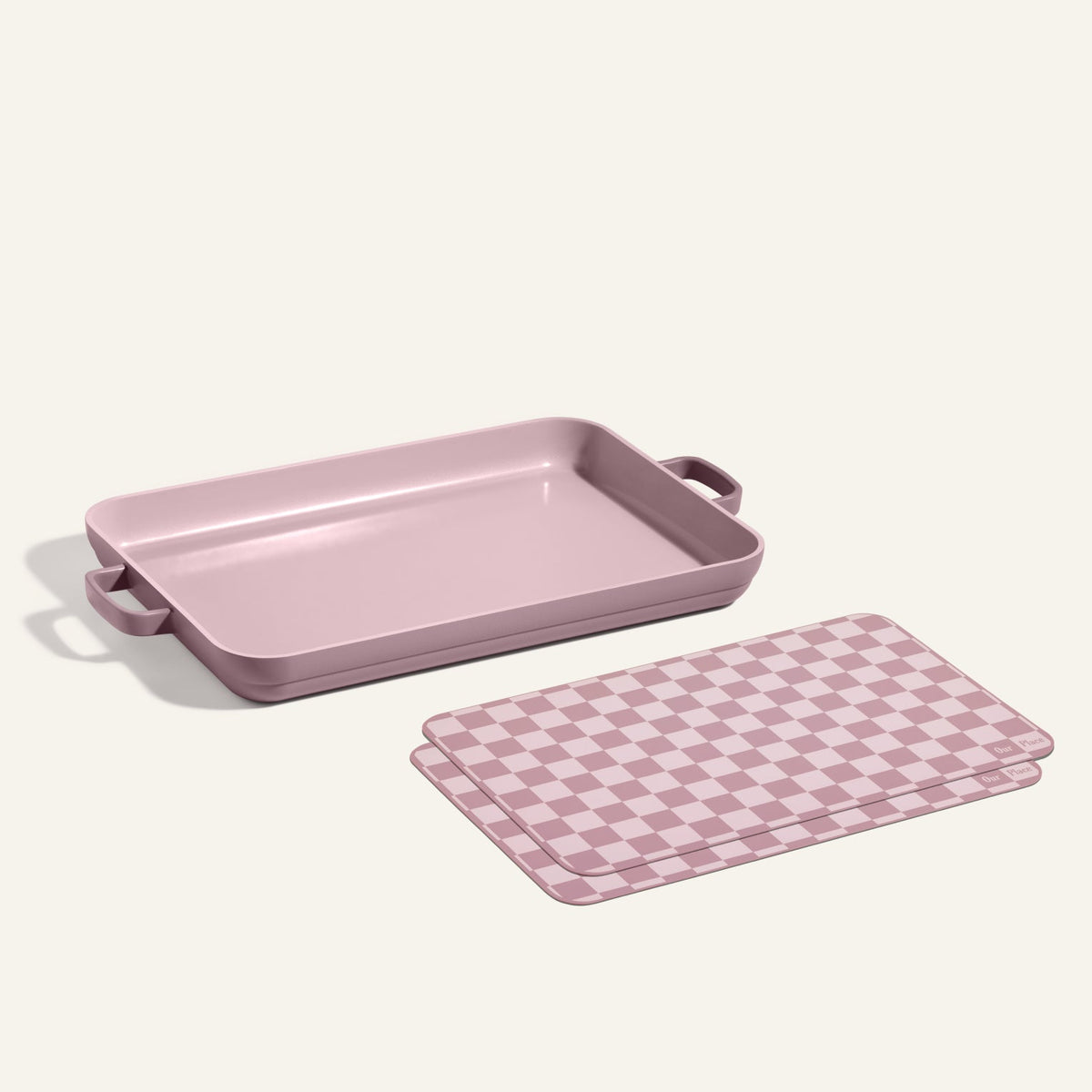 A Griddle Pan with handles sits next to Oven Mats, both featuring mauve and white checkered patterns, on a neutral background.