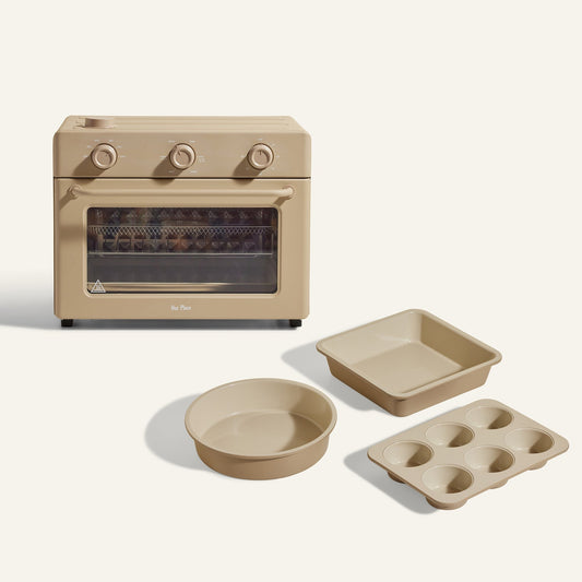 The Large Wonder Oven + Wonder Oven Baker's Kit includes a beige countertop oven with three matching pans—a square pan, a round cake pan, and a six-cup muffin tray—displayed on a light background.