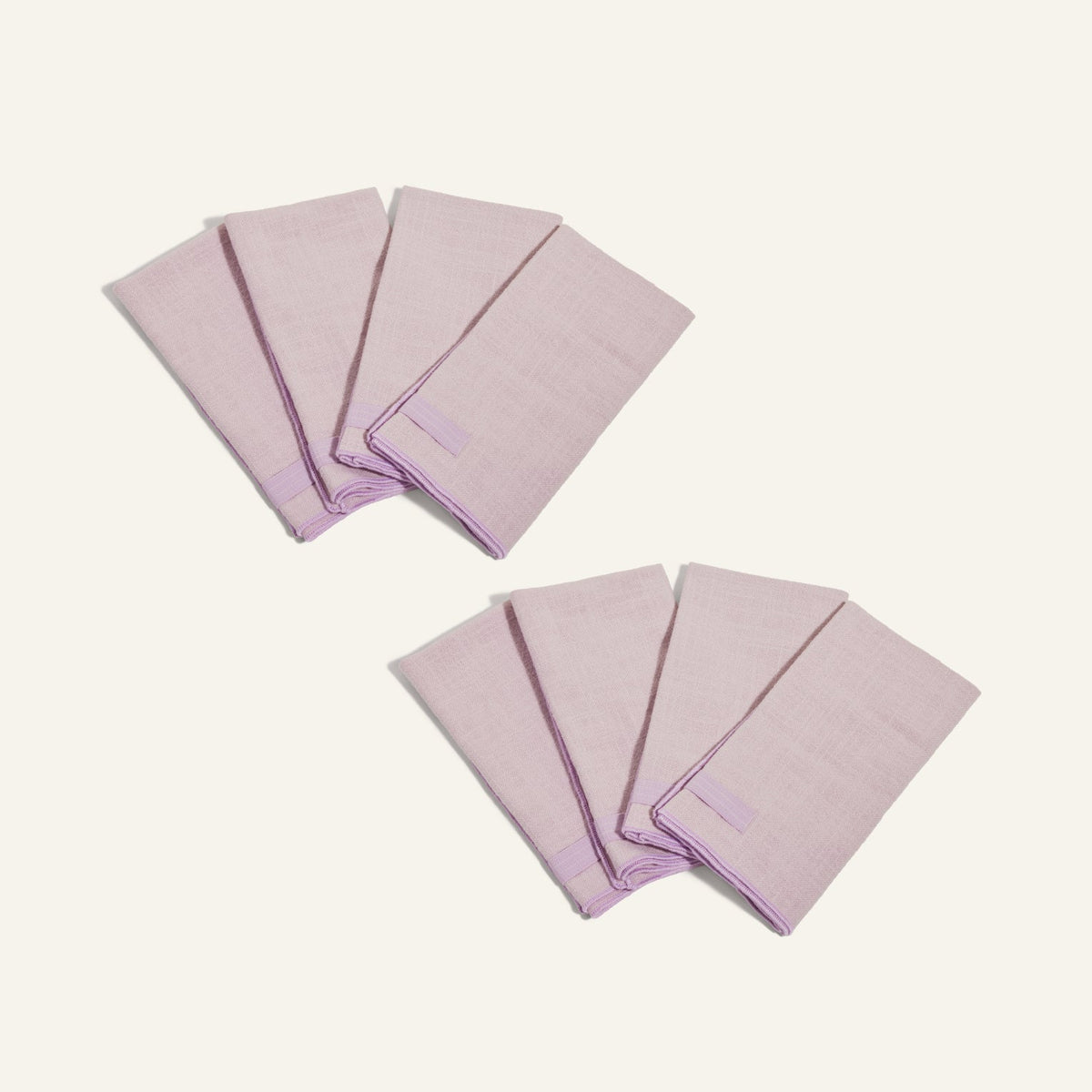 Two sets of four folded light purple Loop Napkins are arranged on a plain light background.