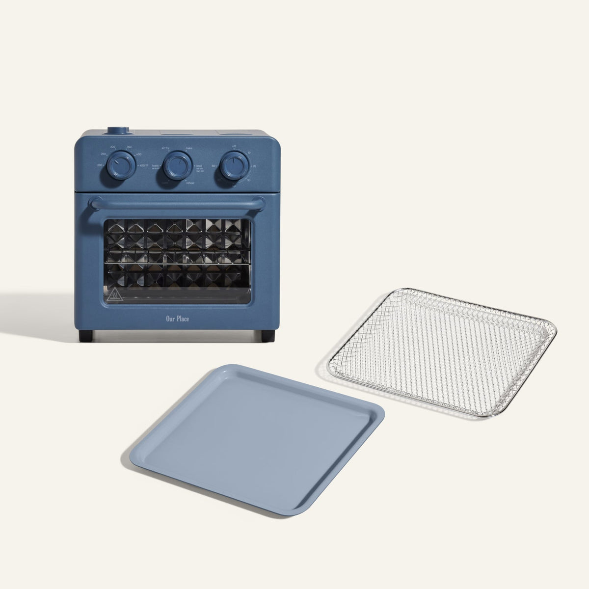 The Wonder Oven + Wonder Oven Essentials Kit is shown in blue, featuring a countertop oven with three dials, a matching baking tray, and a metal mesh tray on a plain light background.