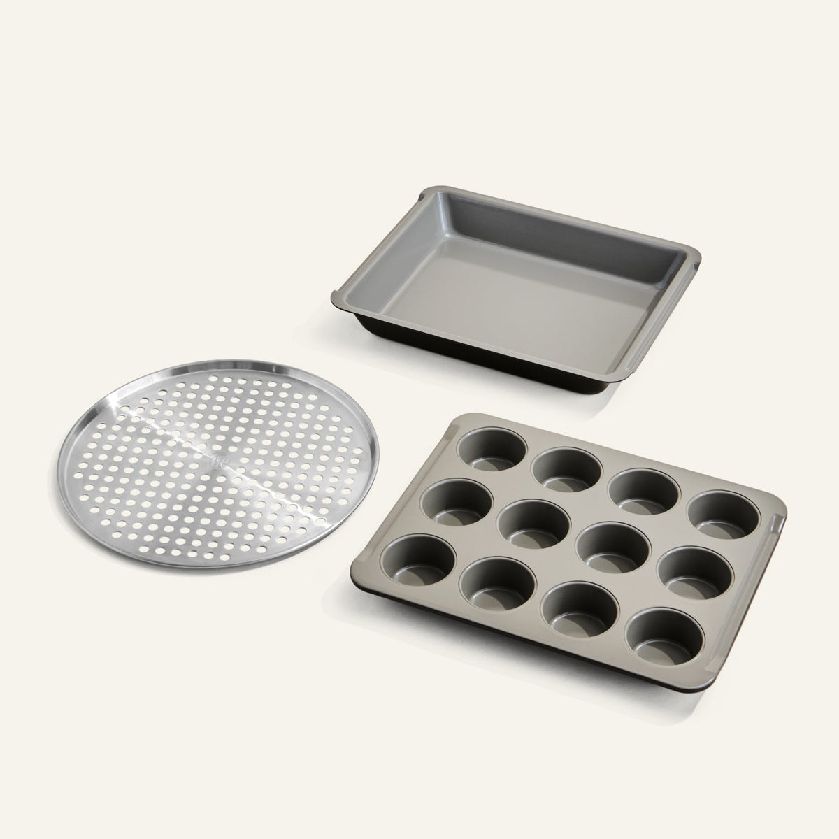 Set of three baking trays including a round perforated tray, a square tray, and a muffin tray on a white background.
