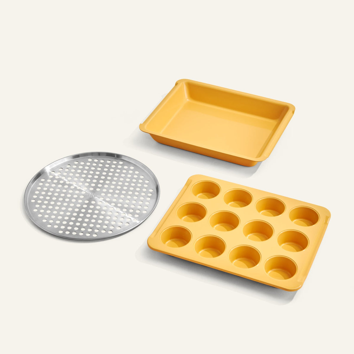 Yellow square baking pan, round perforated pan, and yellow muffin tray on a white background