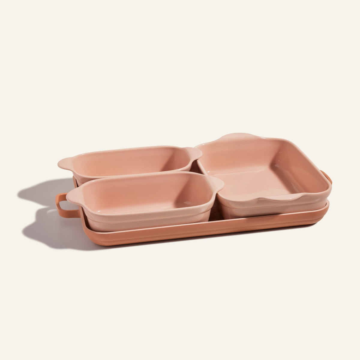 The Bakeware Set features four pink ceramic baking dishes in assorted sizes, stacked elegantly and displayed against a light background.