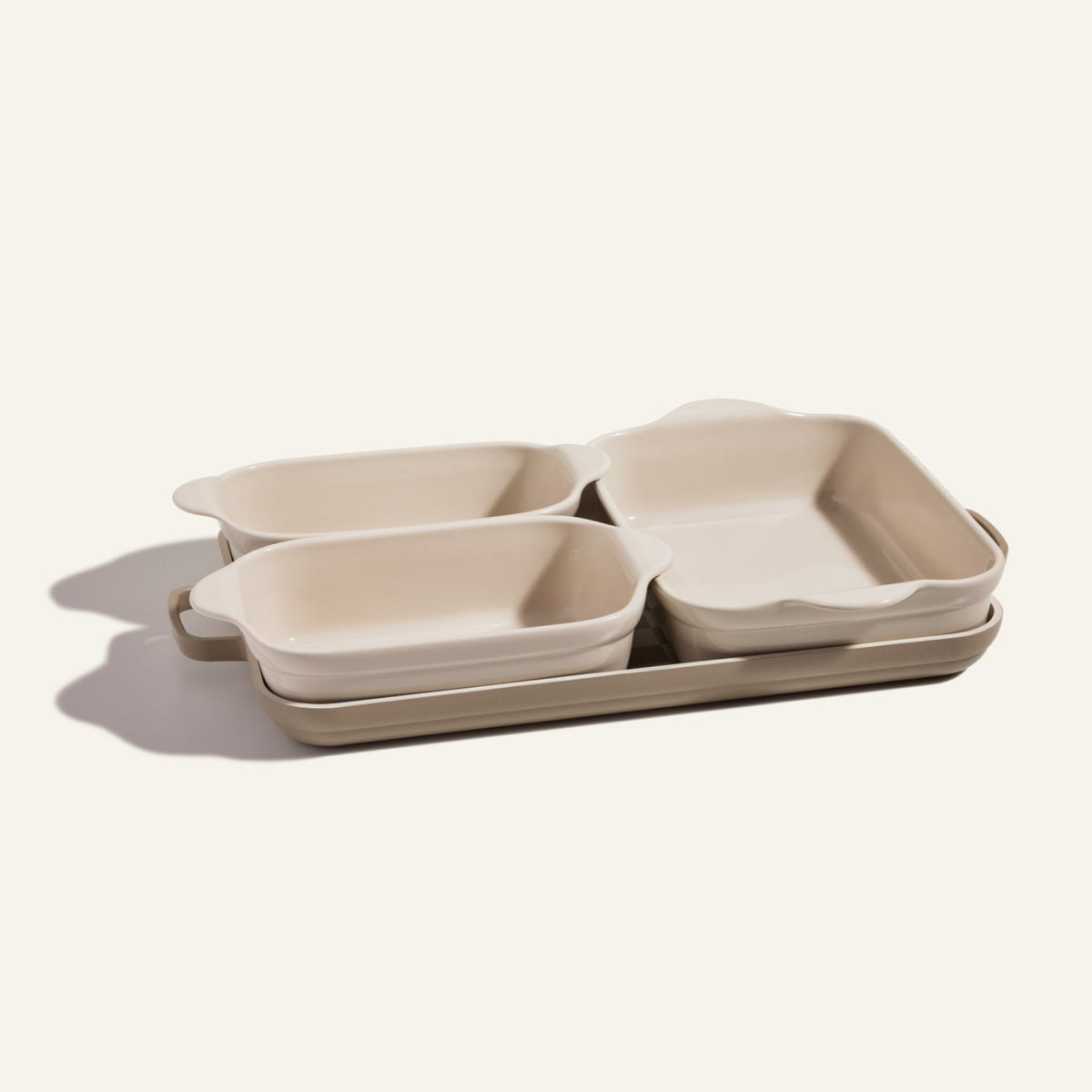 The Bakeware Set includes four cream-colored ceramic baking dishes in assorted sizes, elegantly arranged on a neutral background—perfect for enhancing any kitchen collection.
