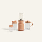 Portable blender with clear cups and pink base on a white background